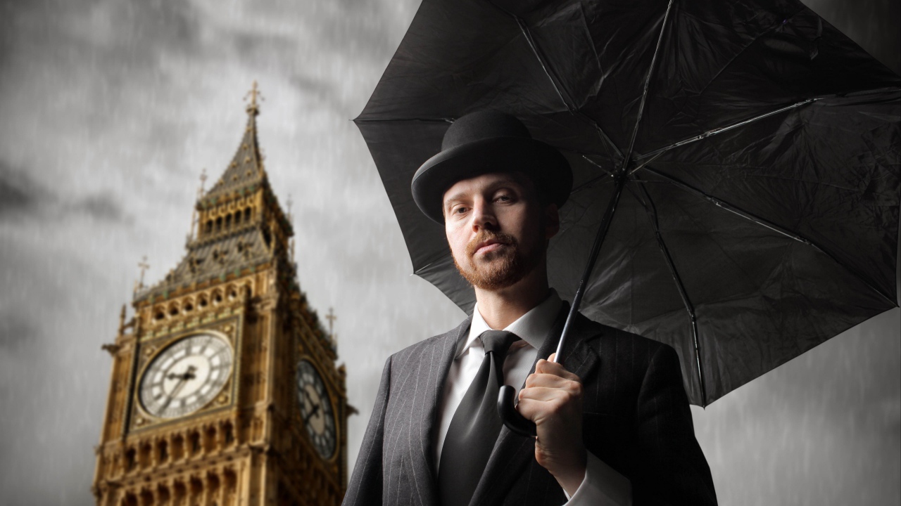 A man in a suit with a black umbrella at the tower with a clock