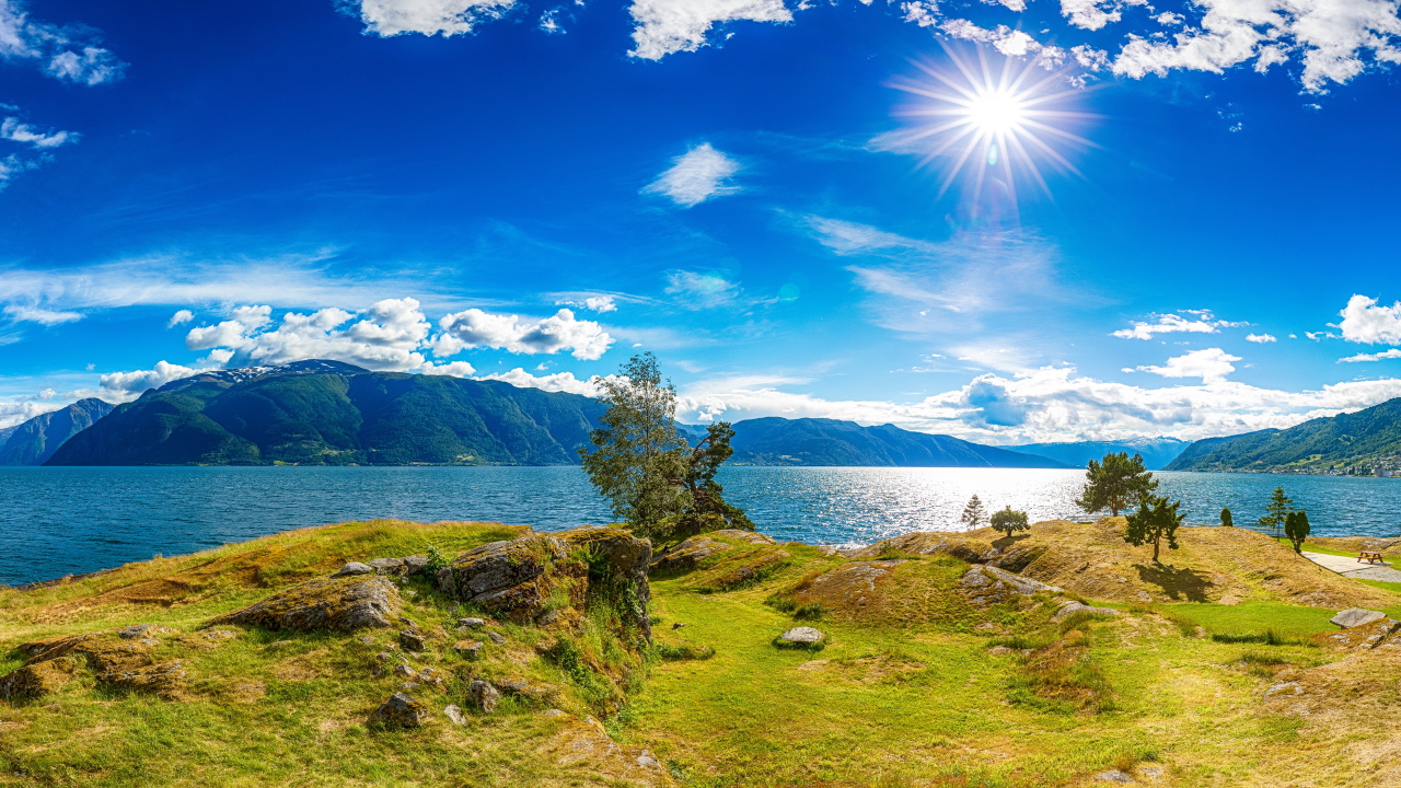 Красивое яркое солнце в голубом небе над горами и водой, Исландия