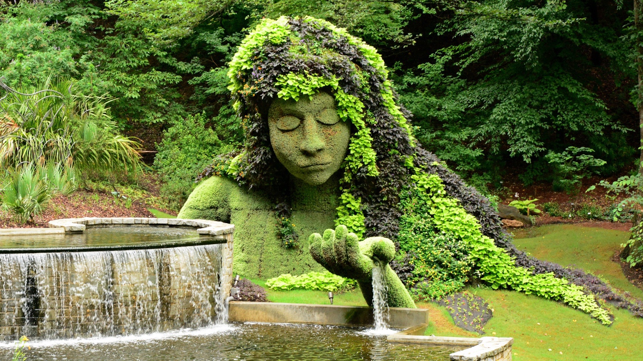 Красивый водопад в парке со скульптурой 