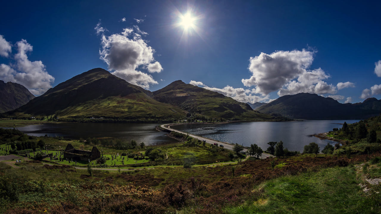 Яркое солнце в голубом небе над горами у реки