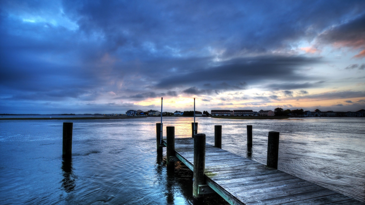 Деревянный мост на реке на фоне неба в сумерках