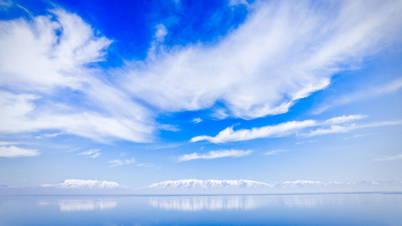 Красивые белые облака над водой около заснеженных гор