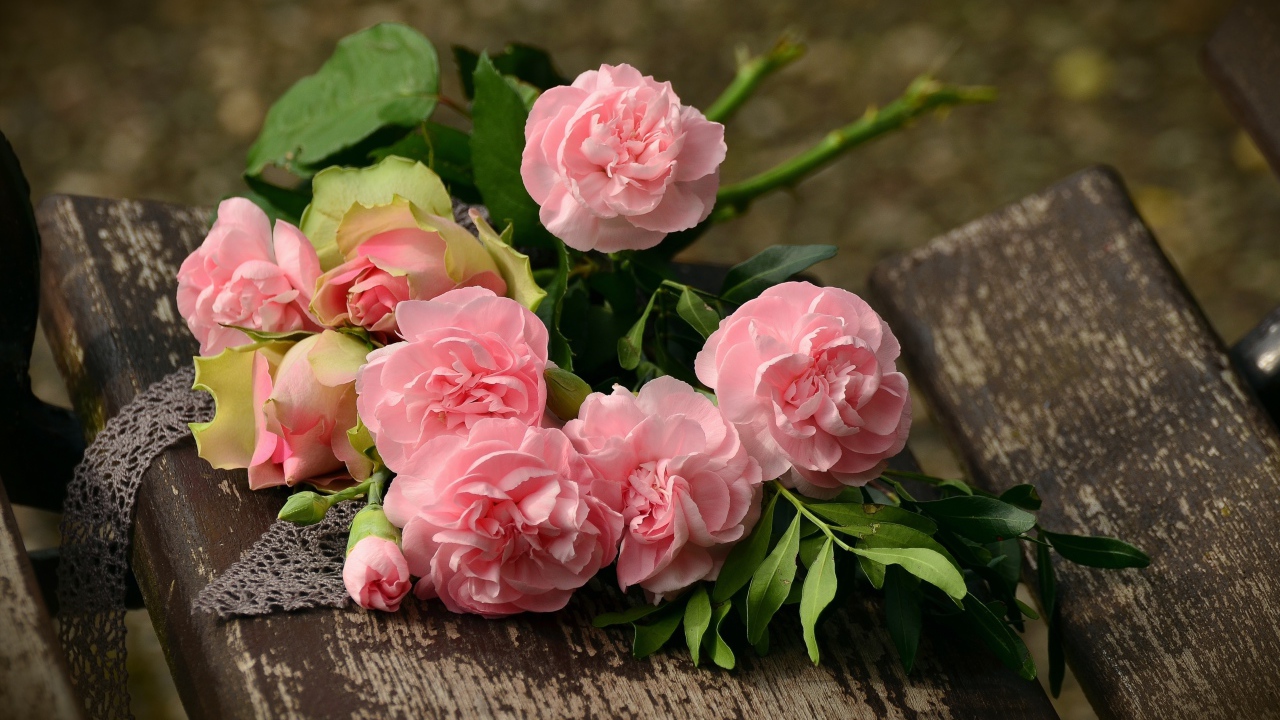 Букет красивых нежных розовых роз лежит на деревянной лавке