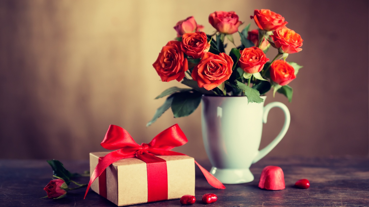 Букет роз в белой вазе с подарком на столе