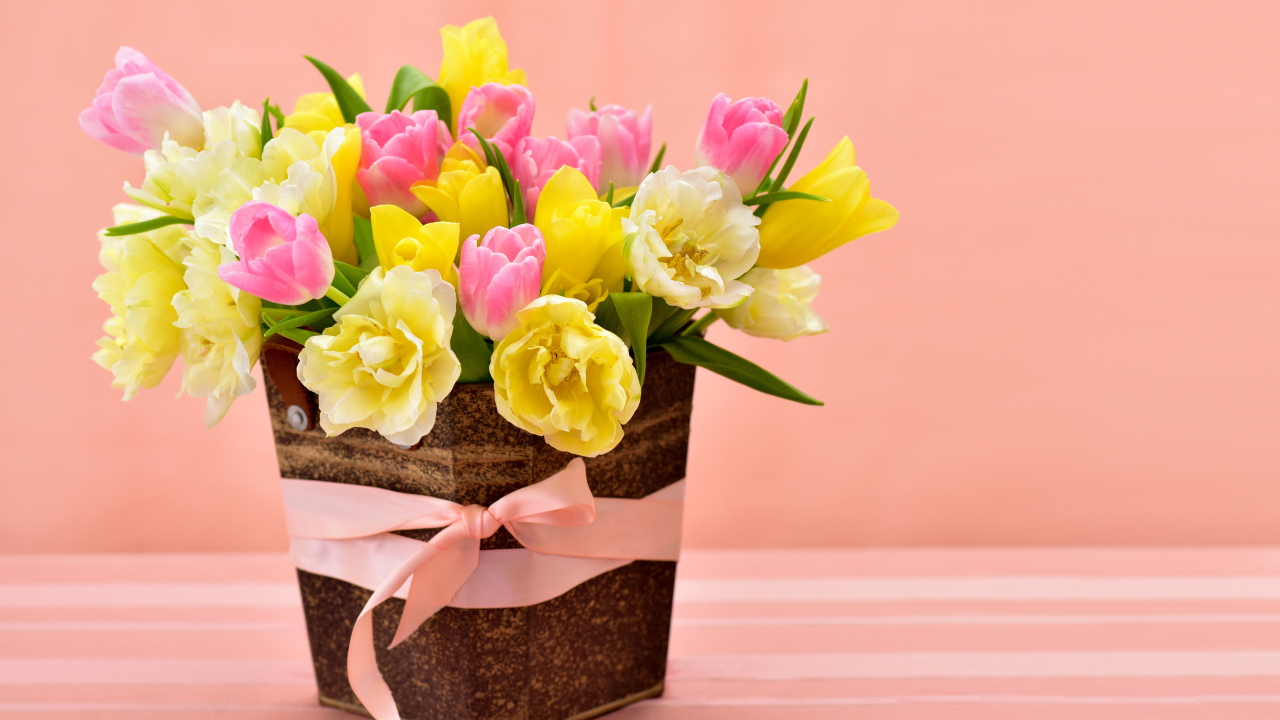 Букет красивых разноцветных тюльпанов в вазе на розовом фоне