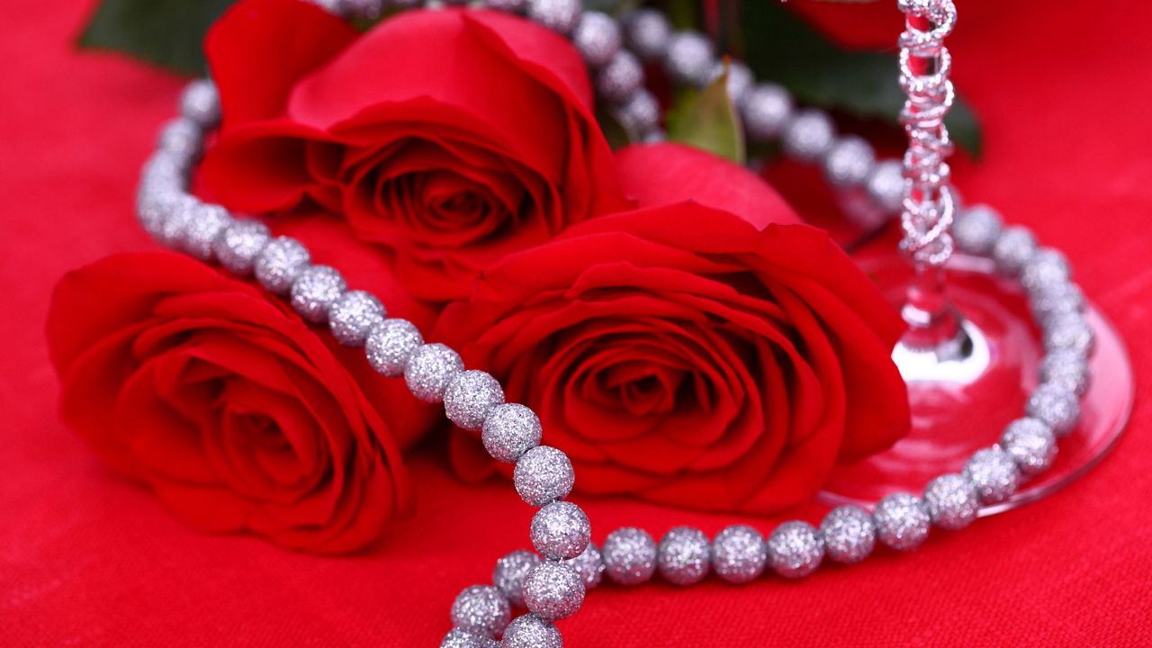 Три красные розы с украшением на красном фоне