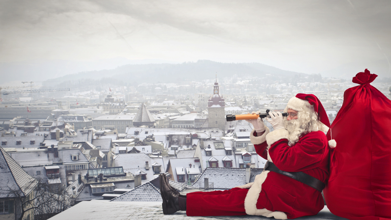 Санта Клаус сидит на крыше дома с большим красным мешком