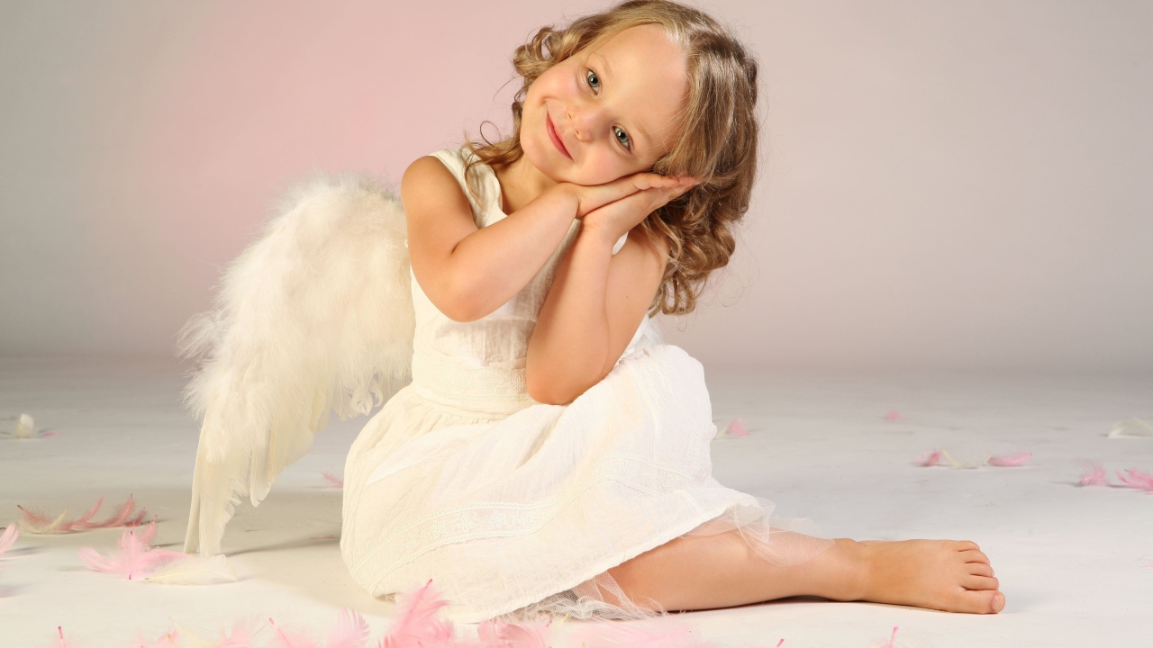 Милая маленькая девочка в белом платье с крыльями ангела