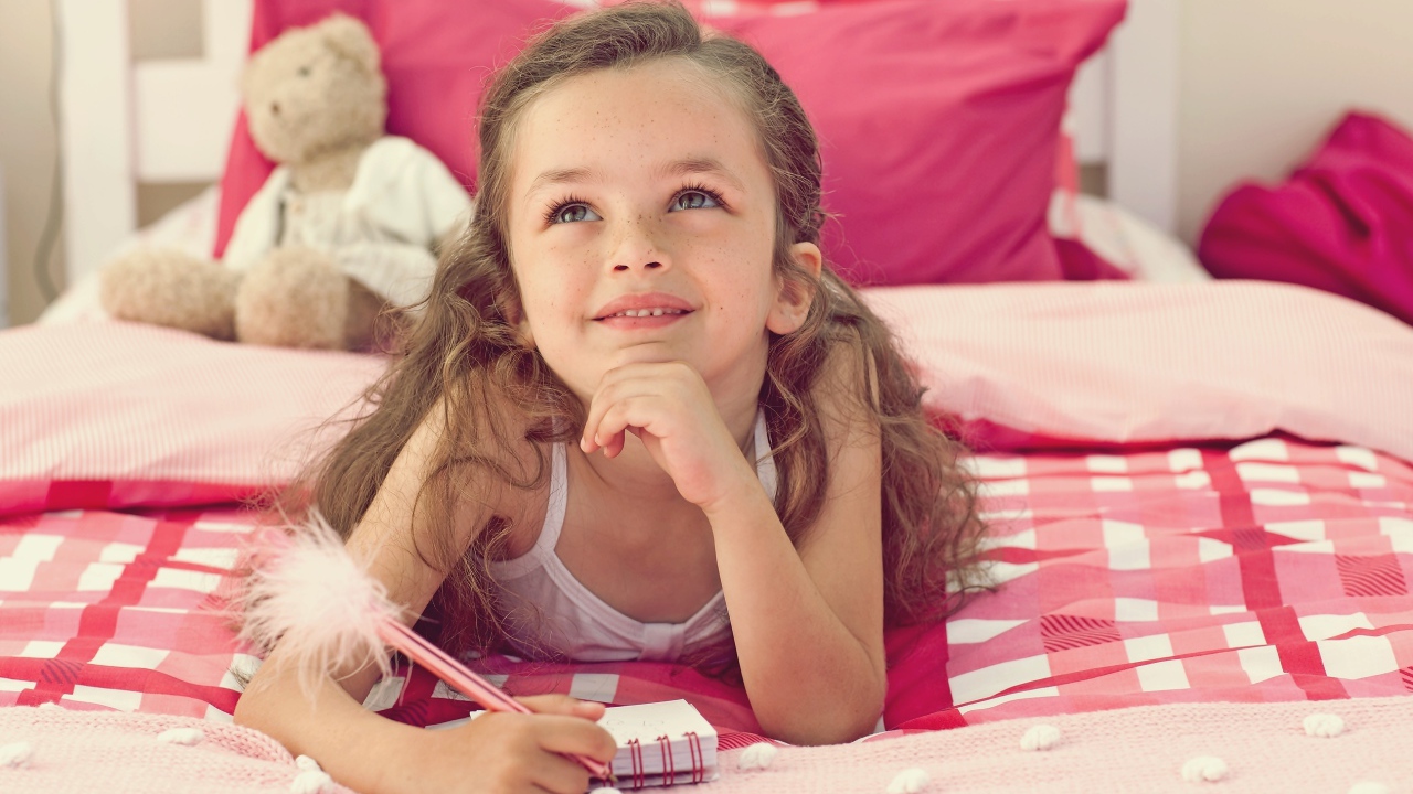 Замечтавшаяся маленькая девочка лежит на кровати