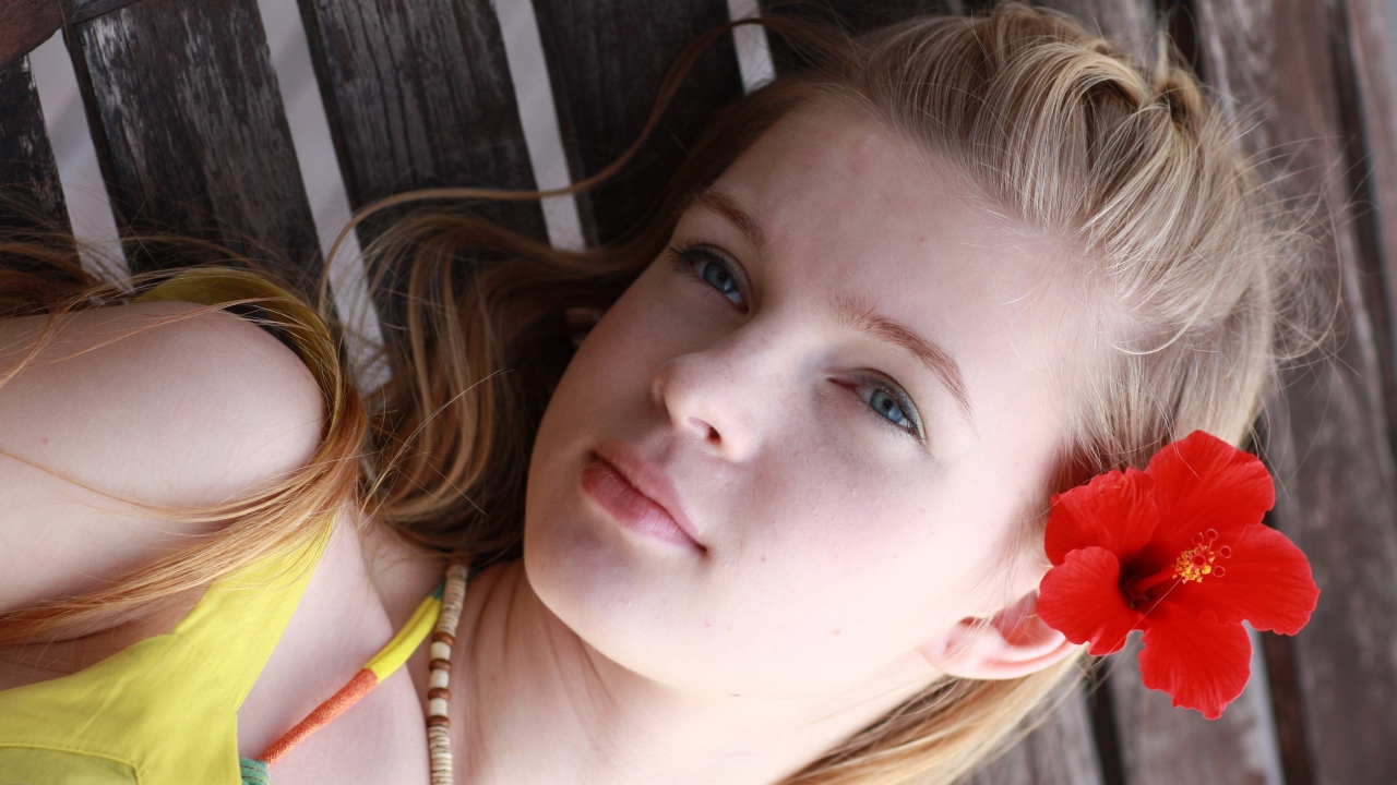 Девочка с красным цветком гибискуса в волосах