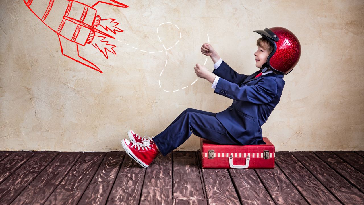 Маленький мальчик в шлеме сидит на чемодане