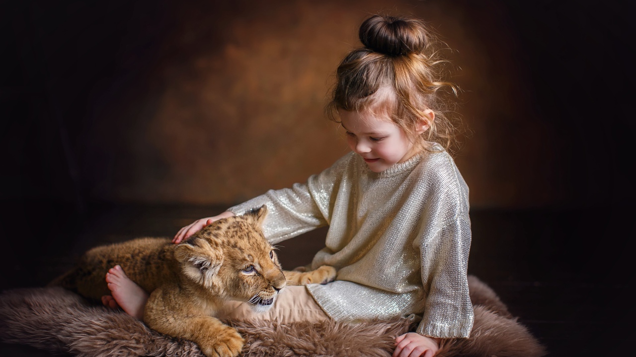 Маленькая девочка гладит маленького львенка