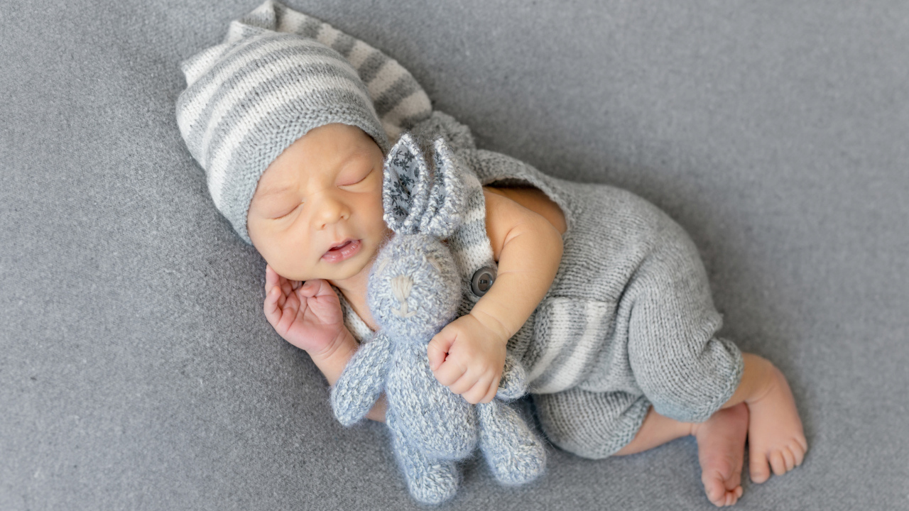Спящий младенец с серым вязаным зайцем