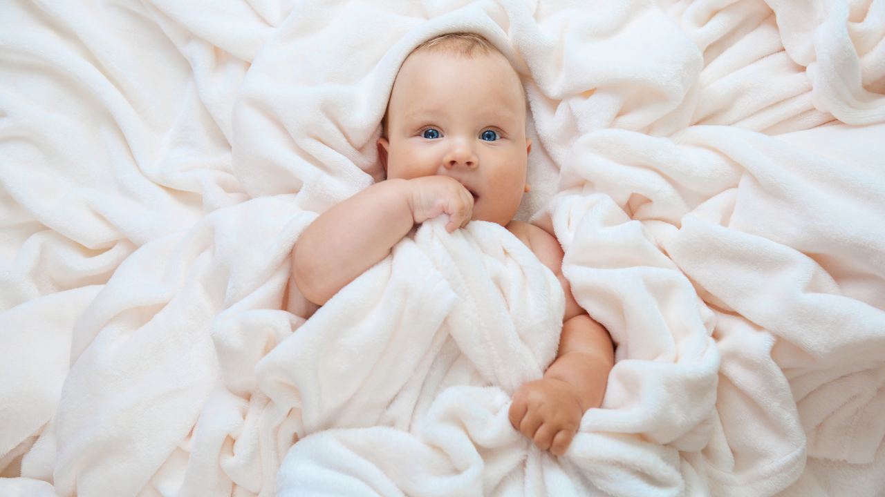 Маленький голубоглазый ребенок в покрывале 