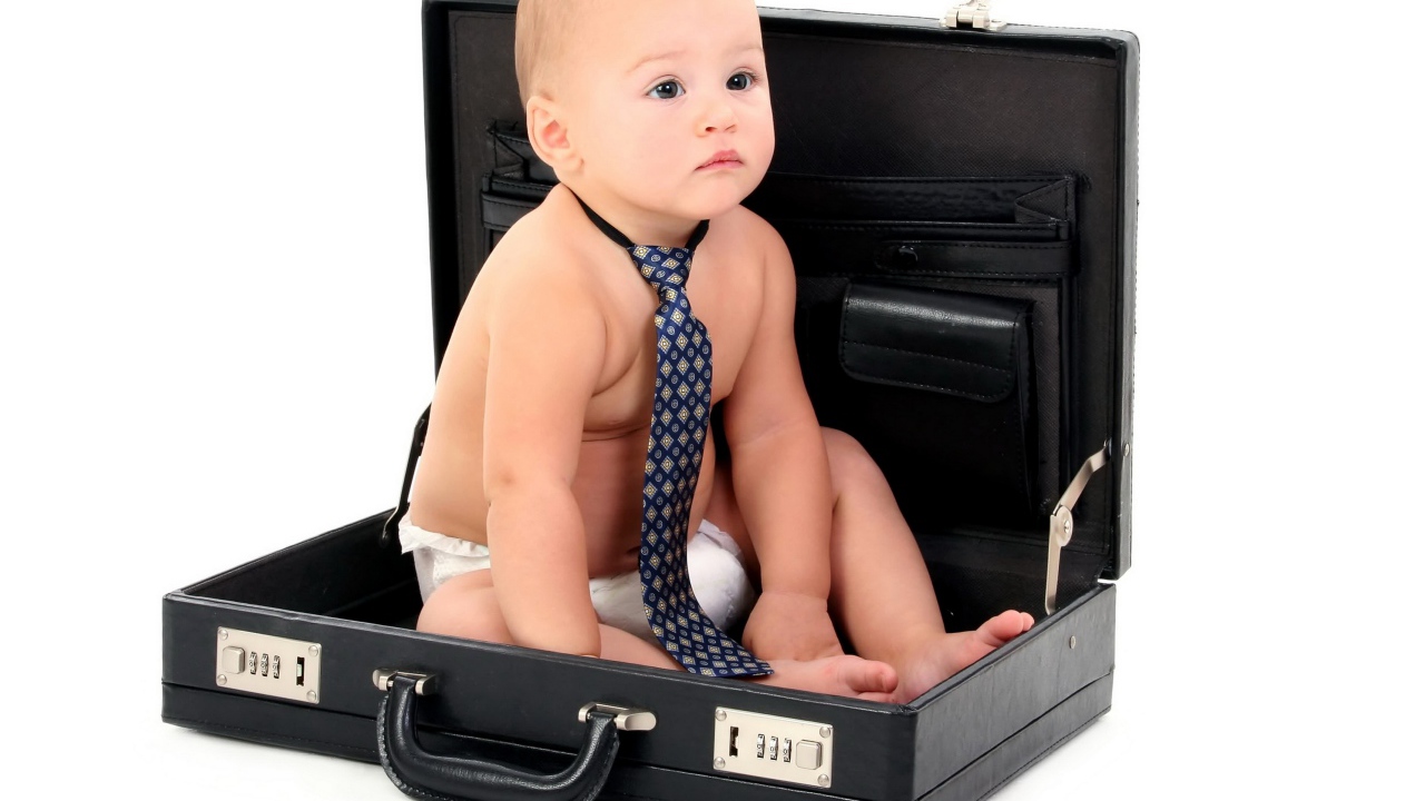 Маленький ребенок в галстуки сидит в кожаном дипломате