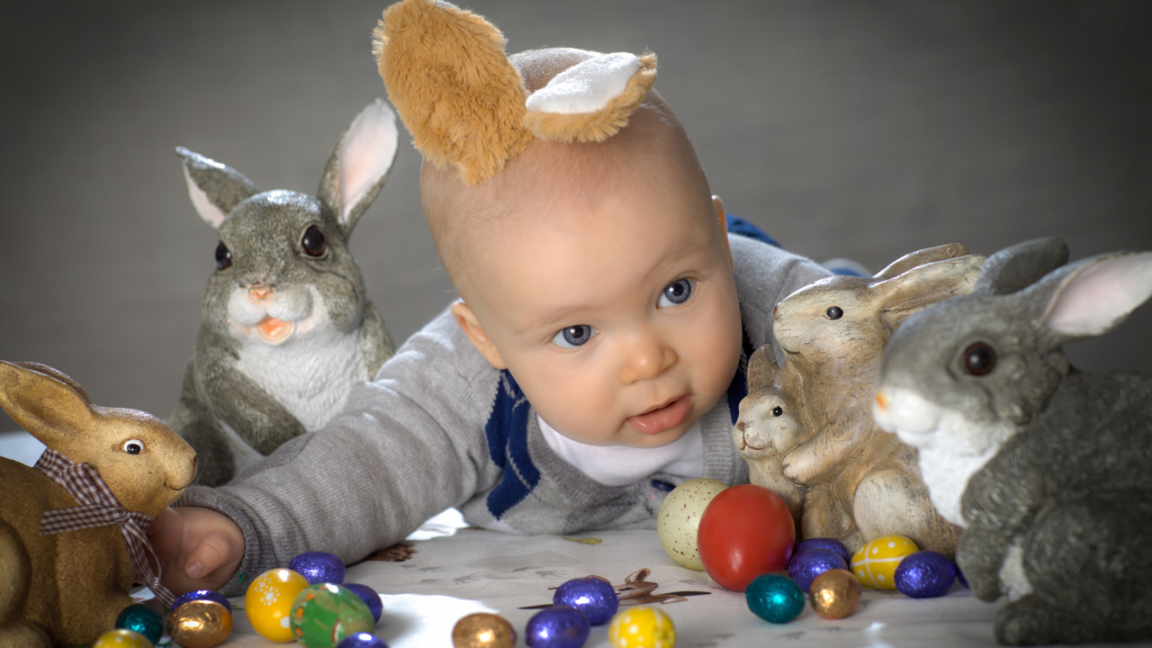 Маленький ребенок с пасхальными кроликами и яйцами