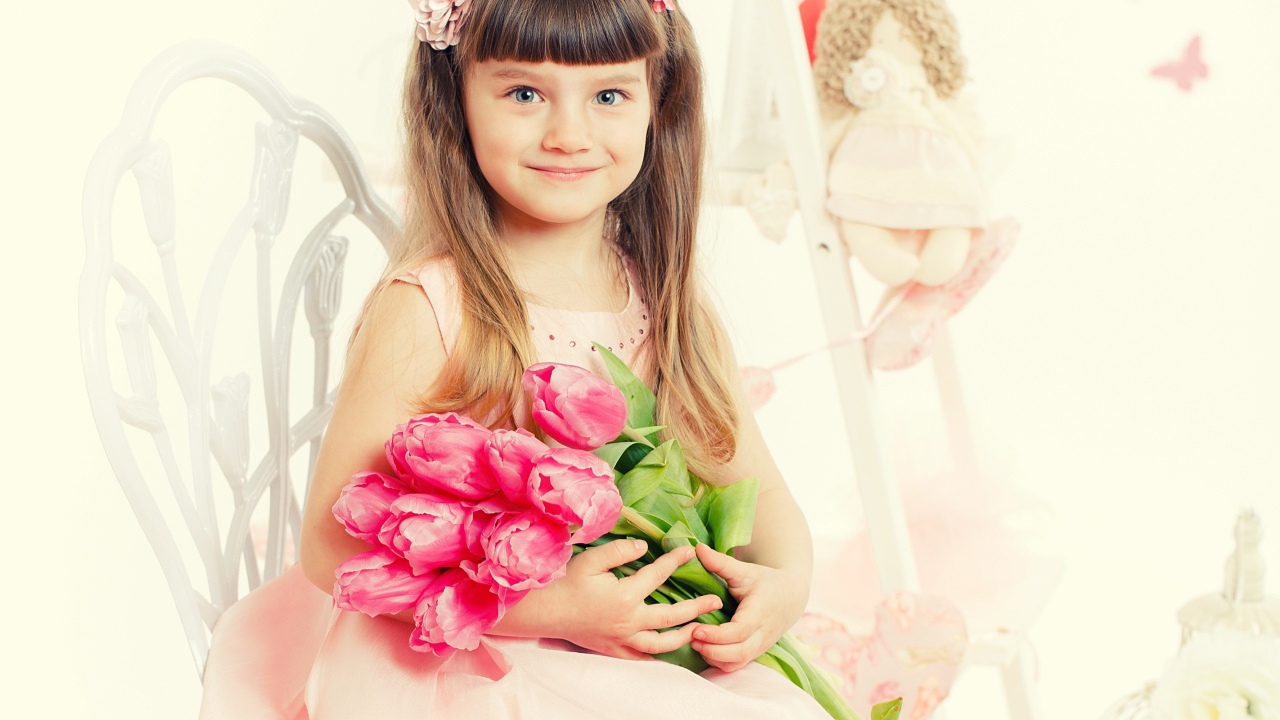 Красивая милая голубоглазая девочка с букетом розовых тюльпанов