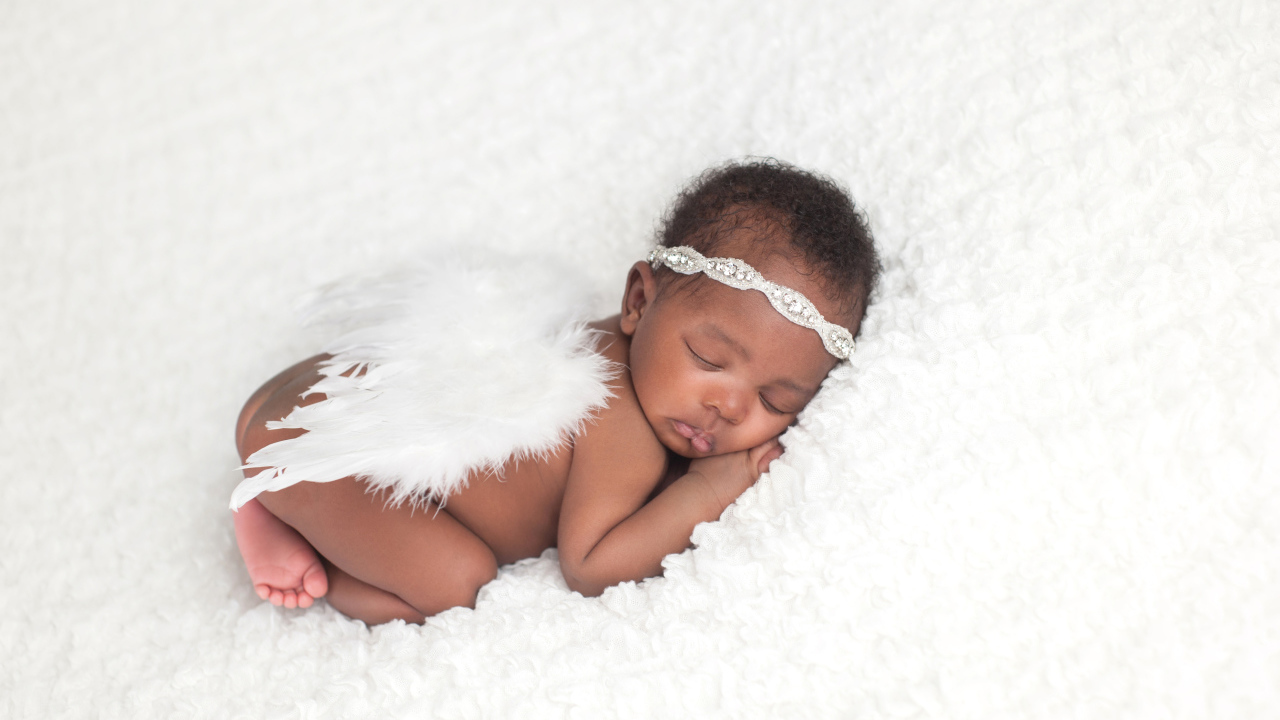 Темнокожий младенец спит с крыльями ангела