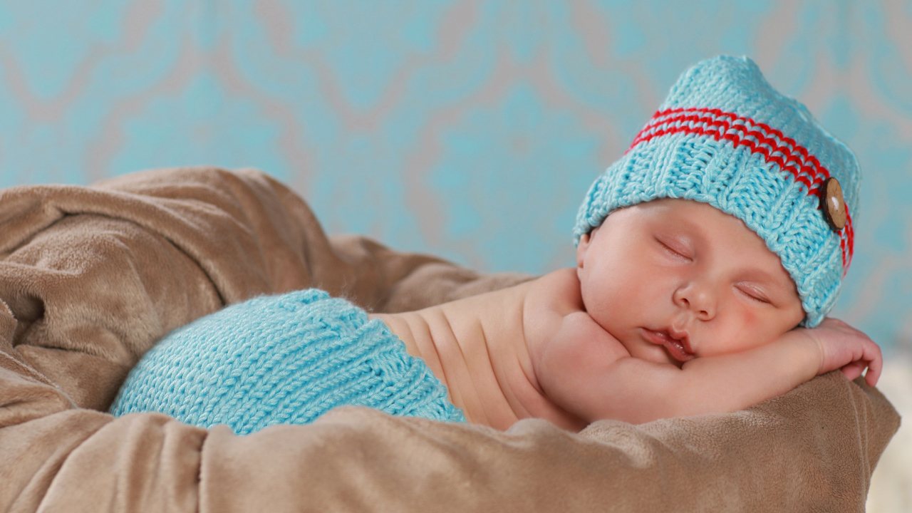 Забавный спящий младенец в голубом вязаном костюме 