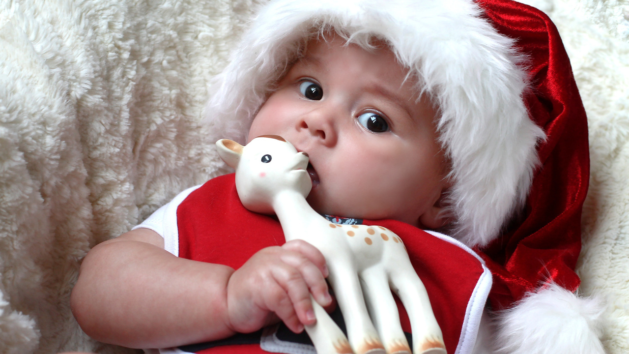 Маленький ребенок в новогодней шапке с игрушкой в руке