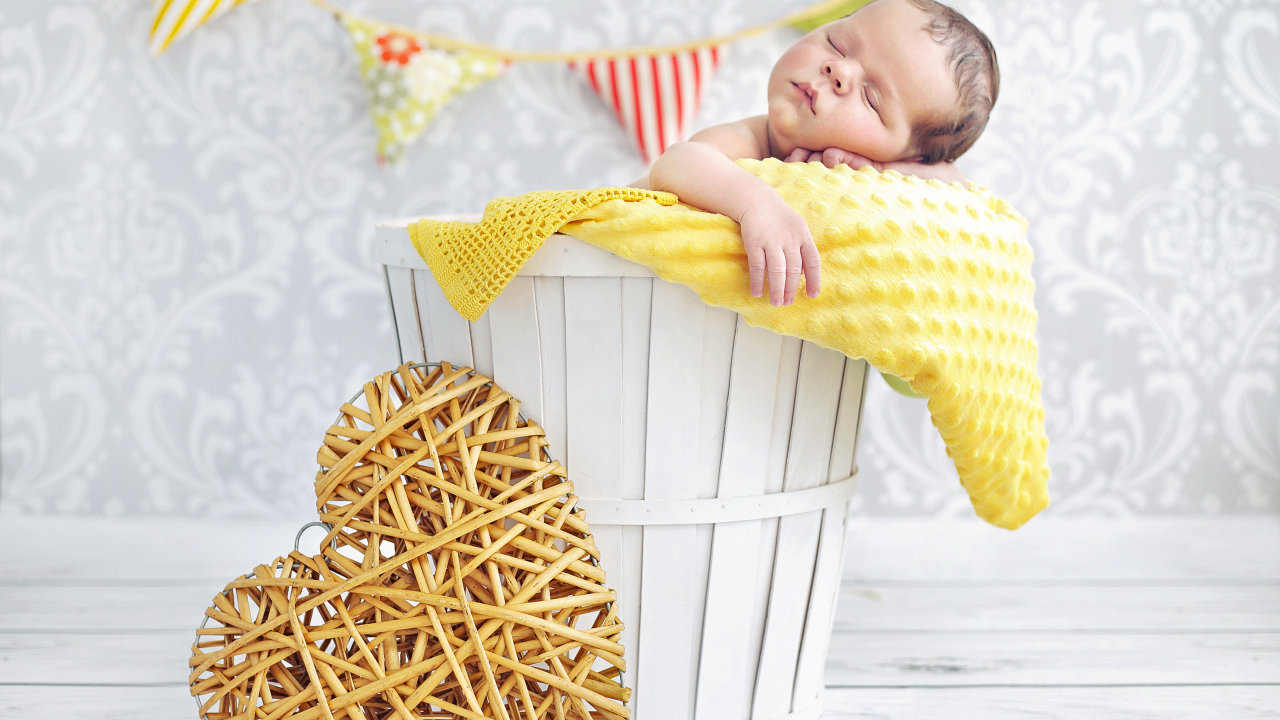 Маленький ребенок спит в корзине с плетеным сердцем