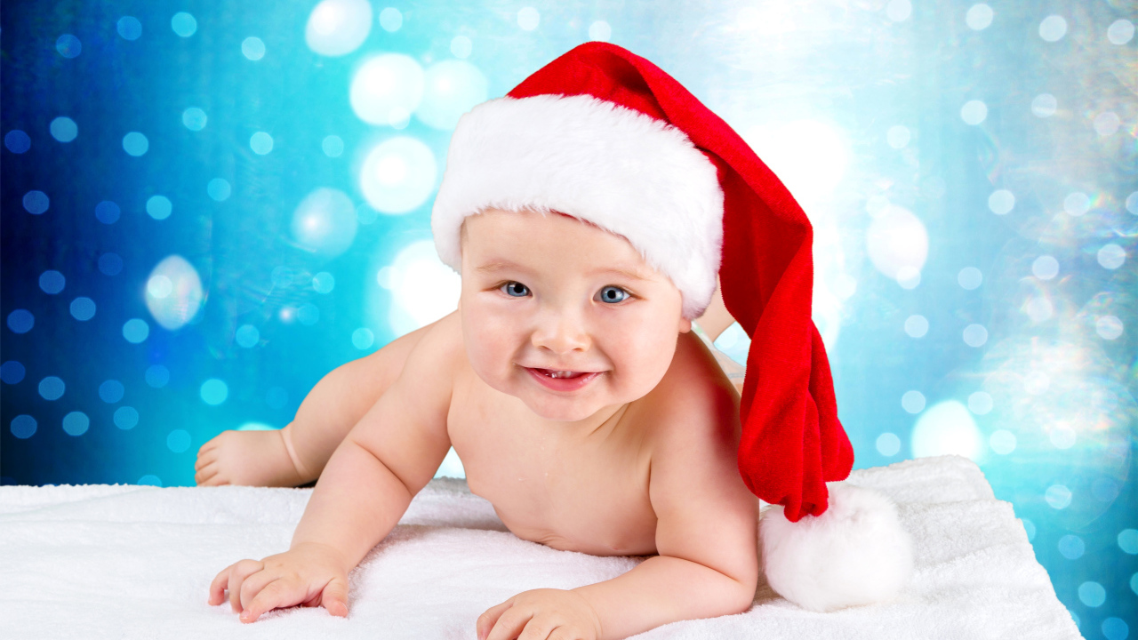 Маленький голубоглазый ребенок в красном новогоднем колпаке