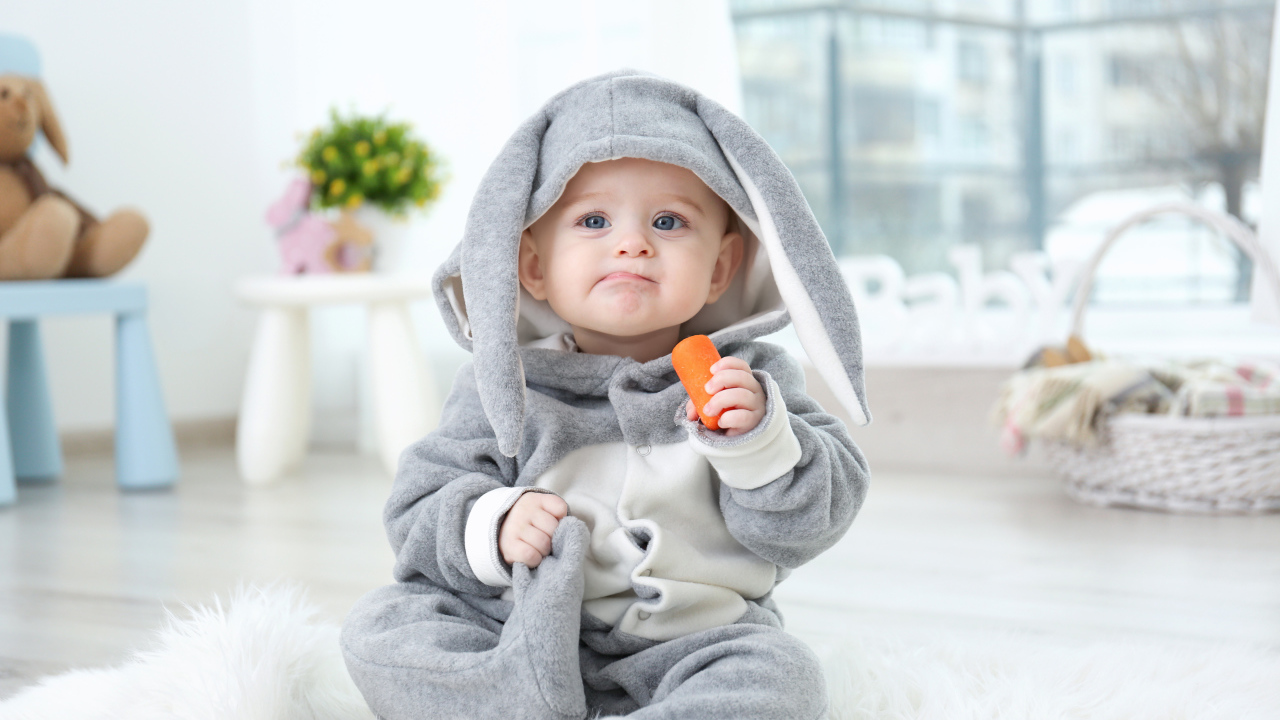 Маленький мальчик в костюме зайчика с морковкой в руке