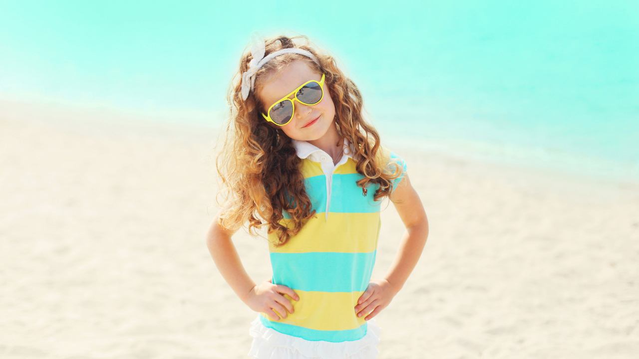 Маленькая модная девочка в солнечных очках на пляже