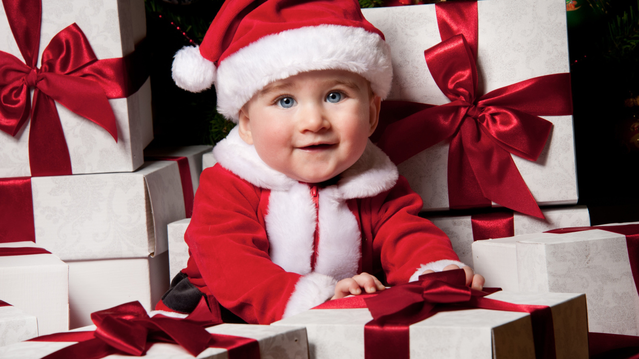 Маленький забавный голубоглазый ребенок в костюме Санты сидит на подарках