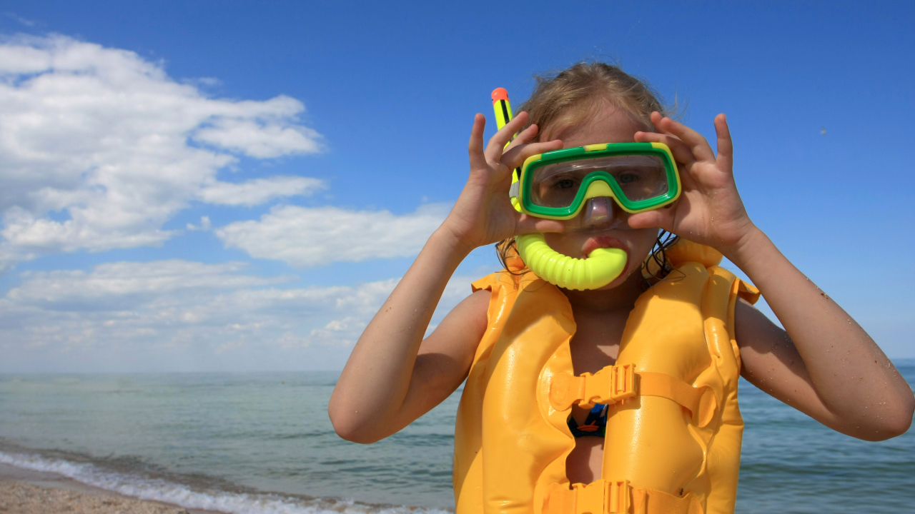 Маленькая девочка в маске и спасательном жилете на море