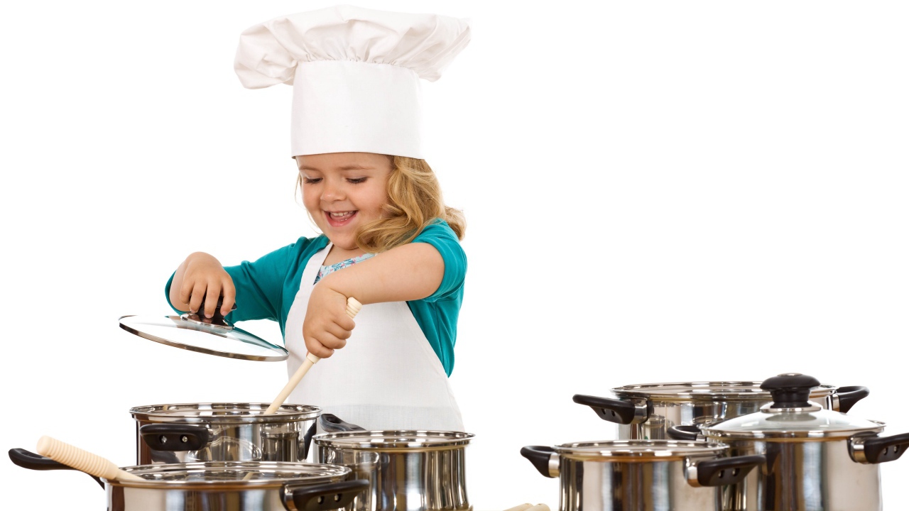 Маленькая девочка в костюме повара на кухне