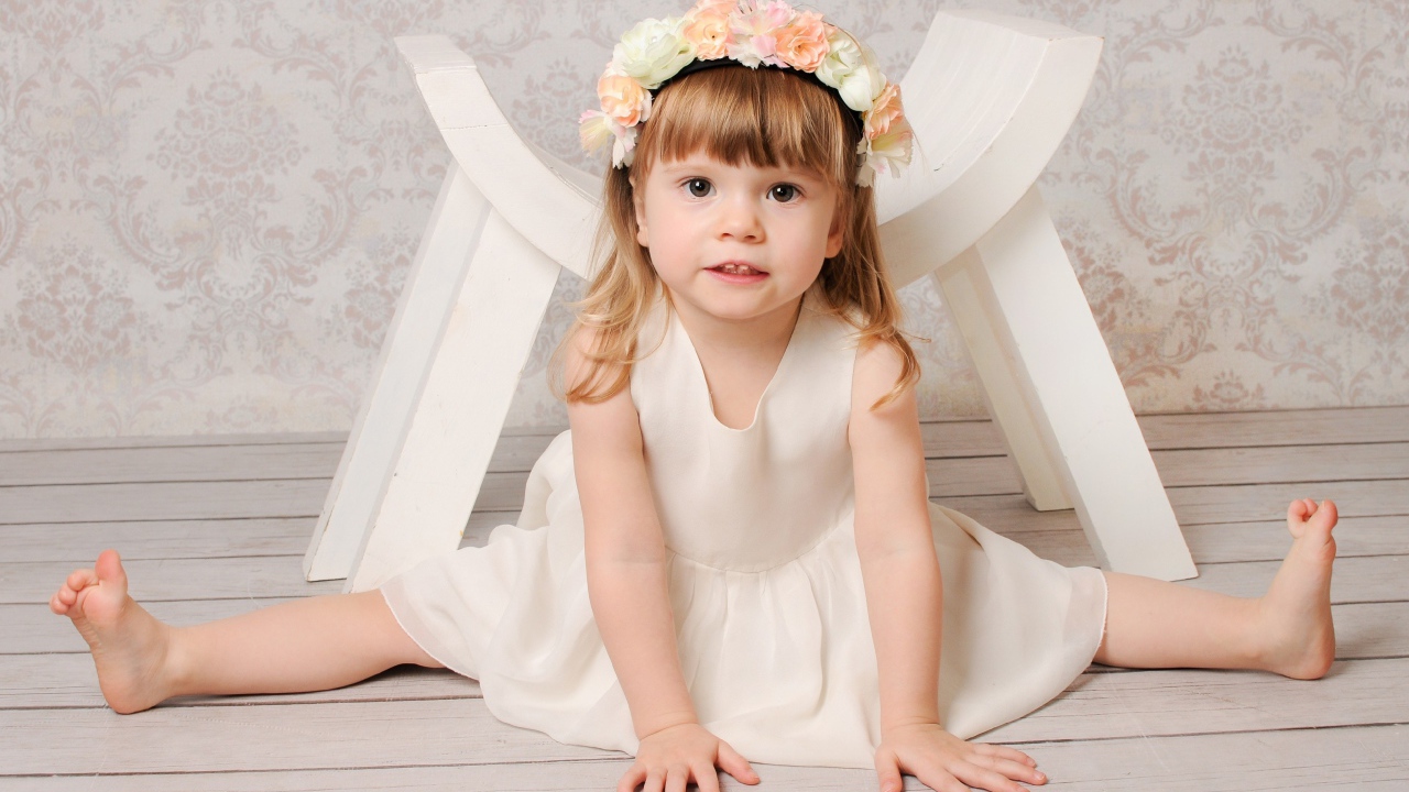 Маленькая девочка сидит на шпагате