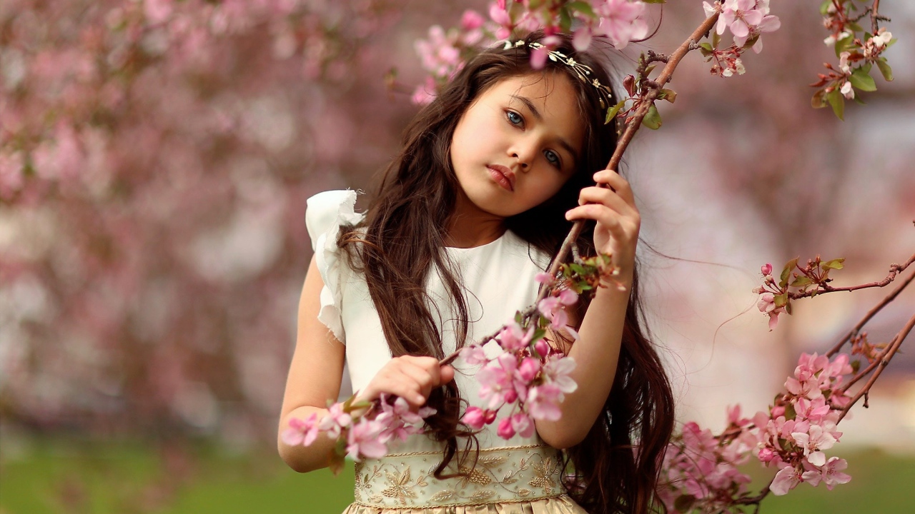Маленькая девочка у цветущей розовыми цветами ветки