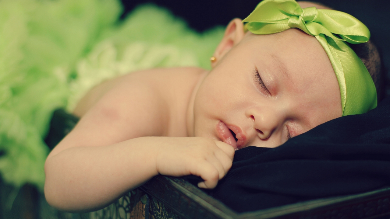 Маленькая спящая девочка с ленточкой на голове