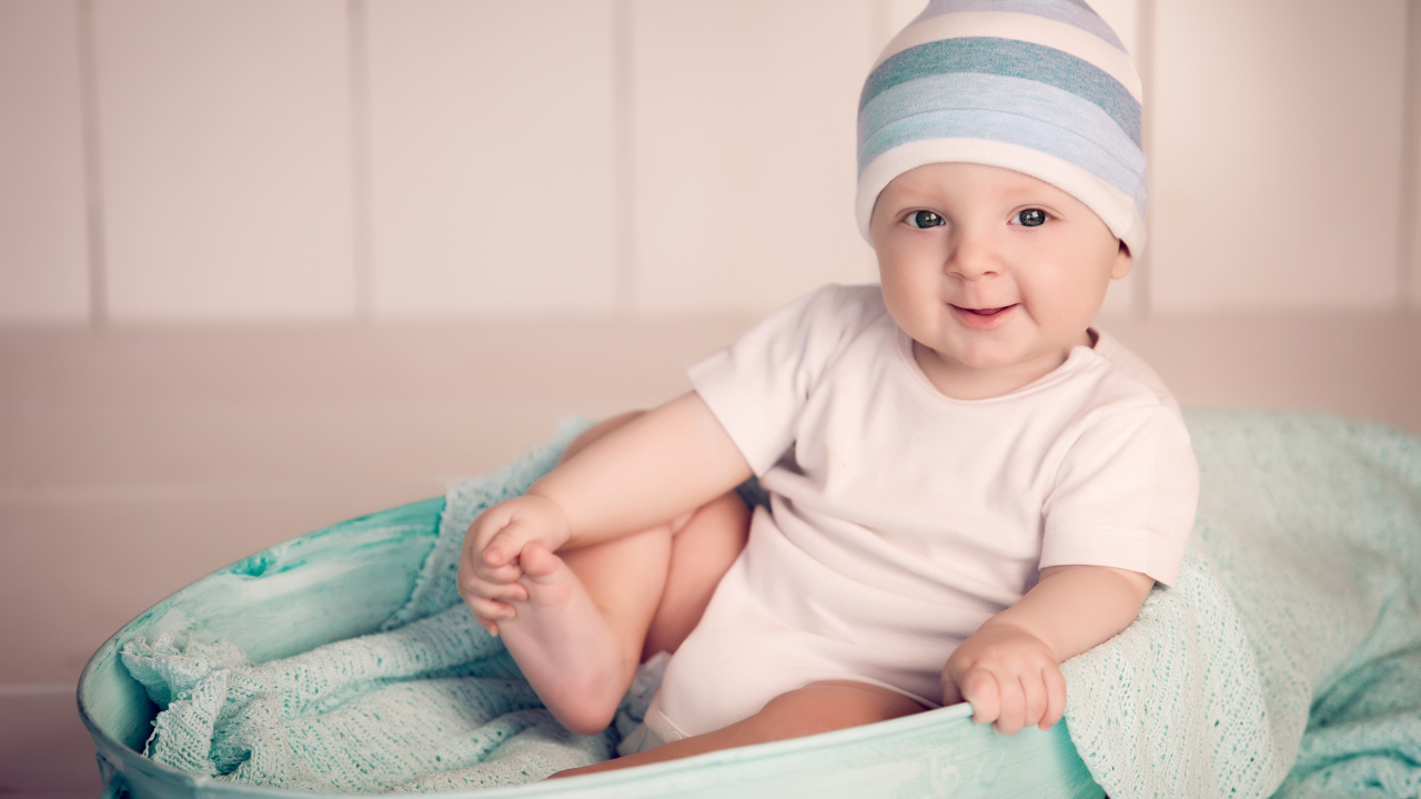 Маленький улыбающийся ребенок сидит в железном тазике