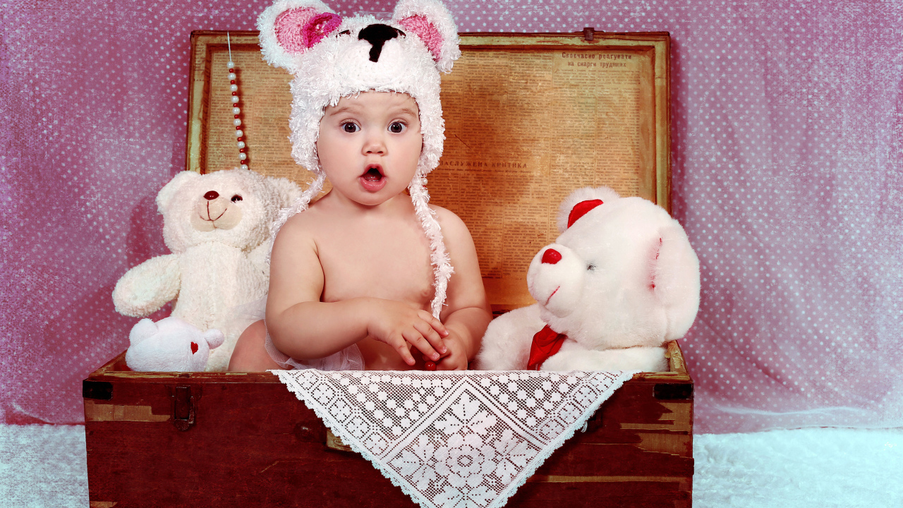 Маленький удивленный ребенок сидит в чемодане с игрушками