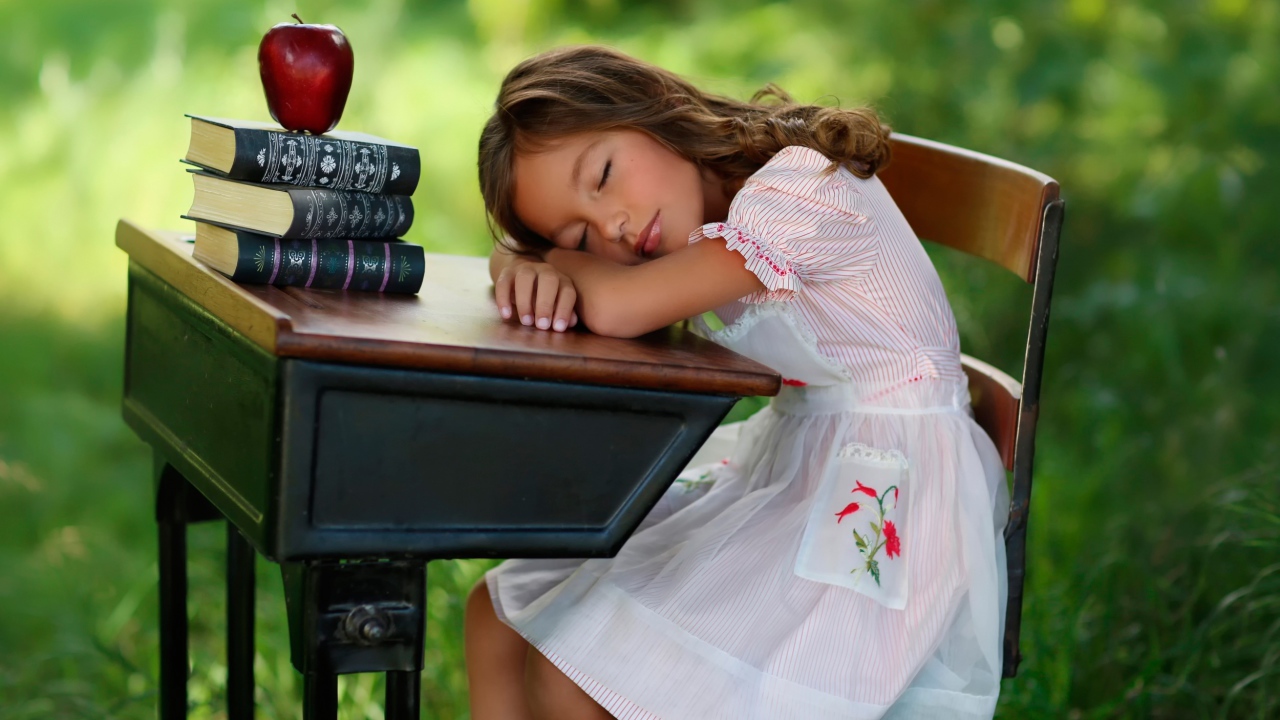 Уставшая маленькая ученица уснула за партой