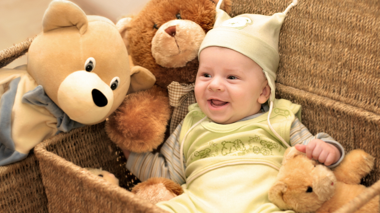 Грудной улыбающийся ребенок в корзине с игрушками