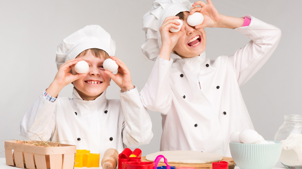 Два маленьких мальчиках в костюмах повара на кухне