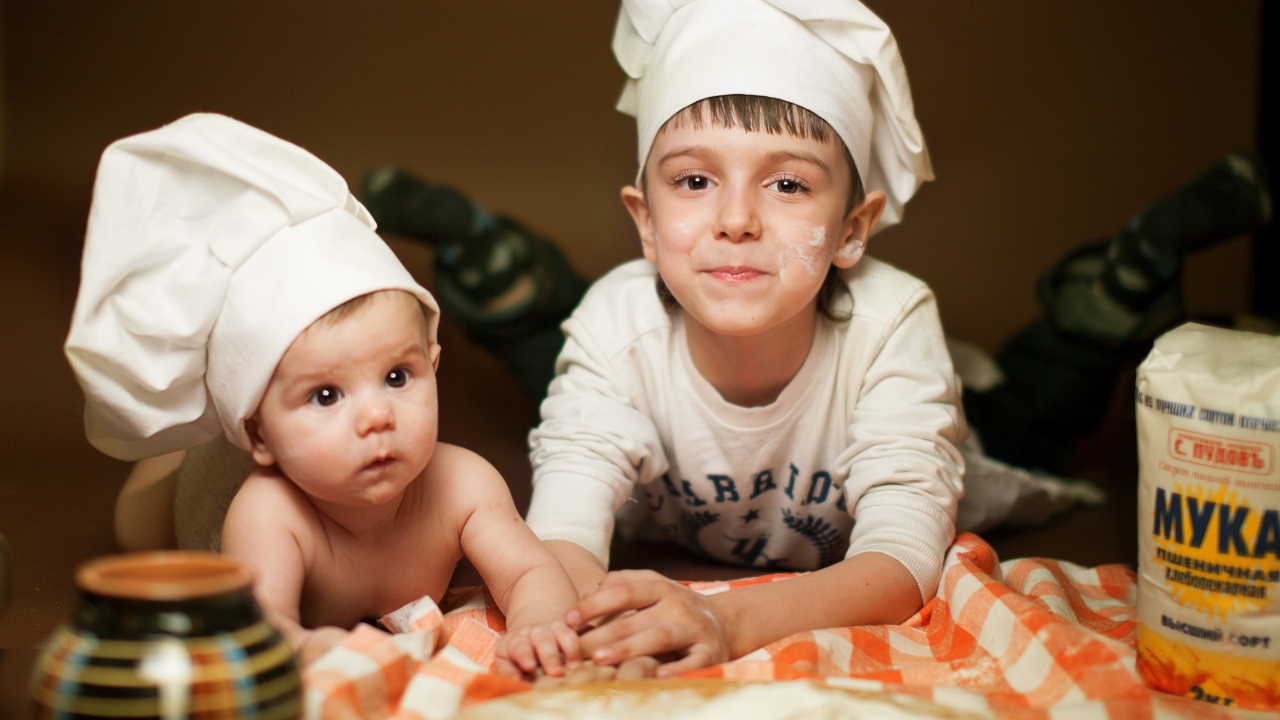 Два маленьких мальчика в шапках повара на кухне