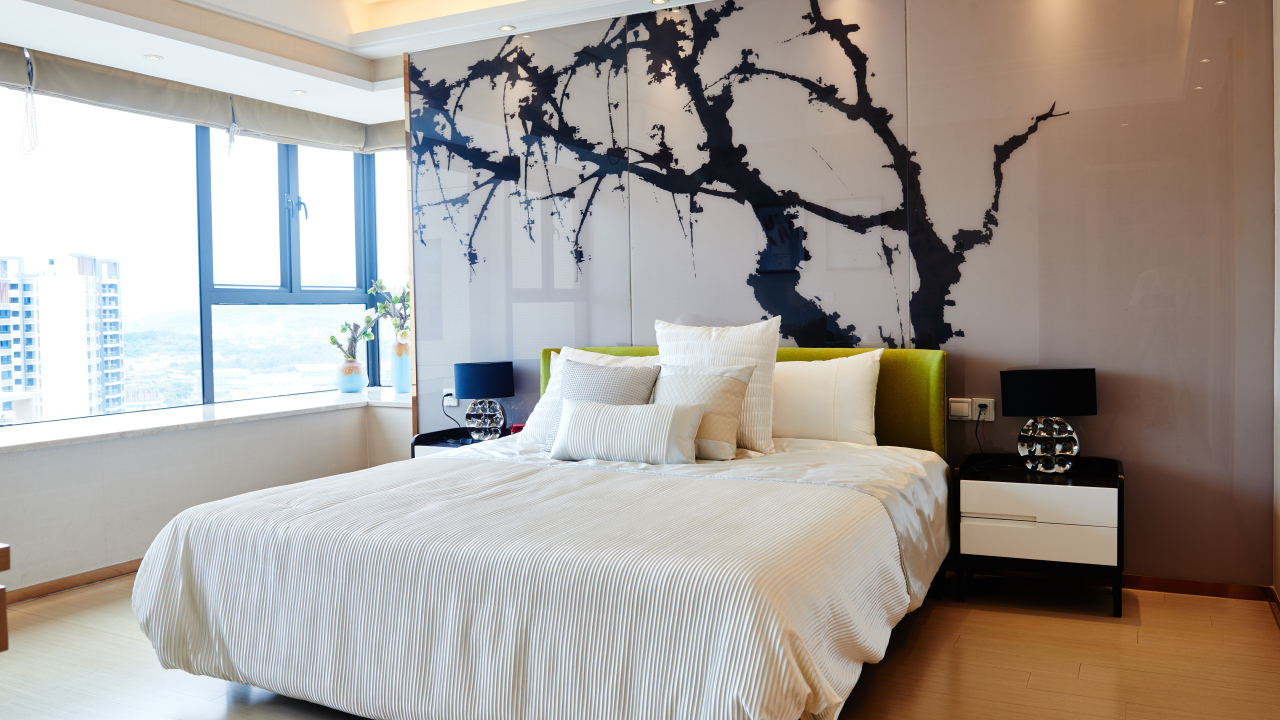 Красивая светлая спальня с большой кроватью и рисунком на стене 