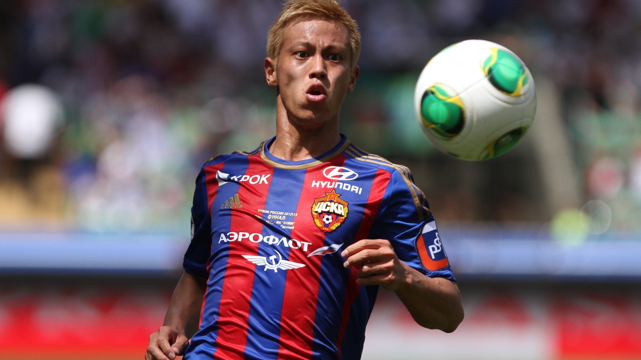 Японский футболист Кэйсукэ Хонда отбивает мяч на поле