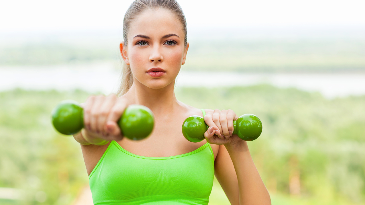 Молодая спортивная блондинка с гантелями в руках