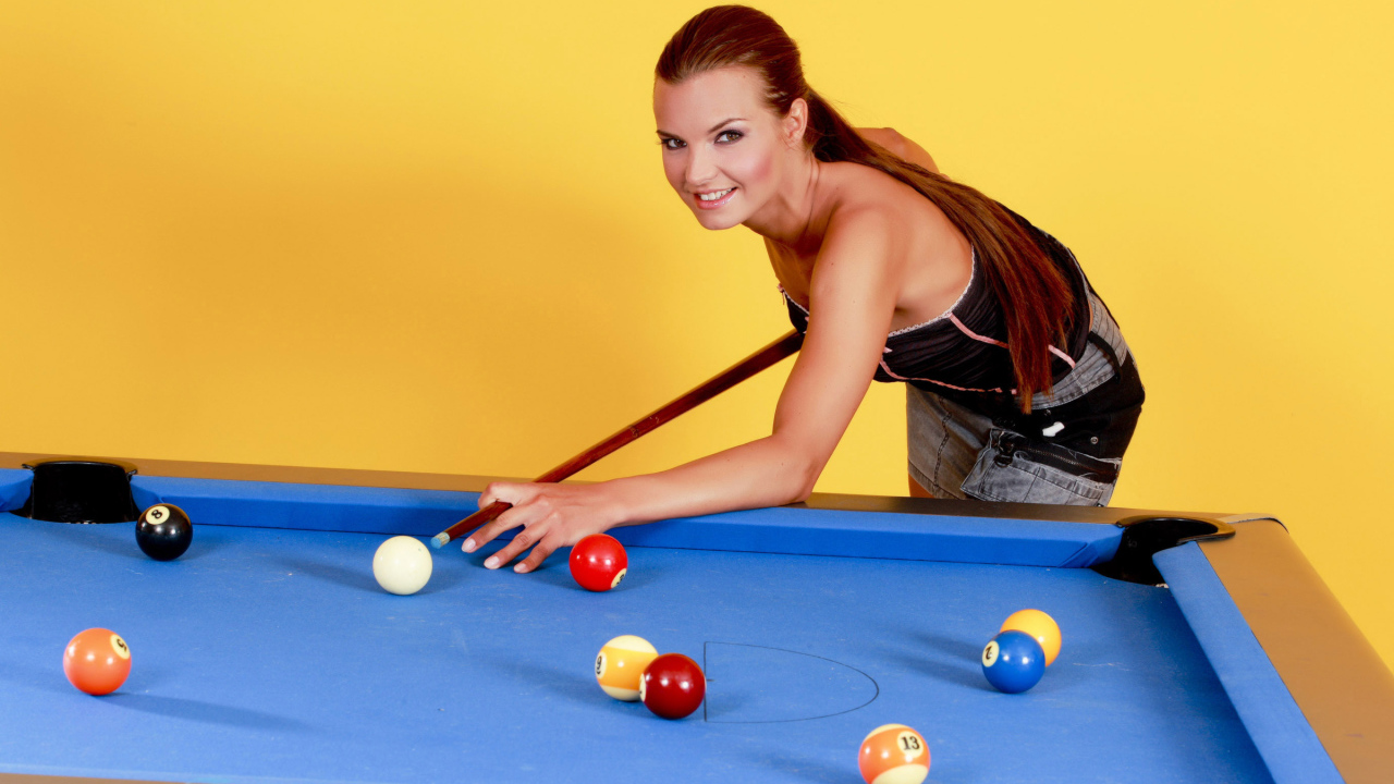 Молодая девушка играет в бильярд
