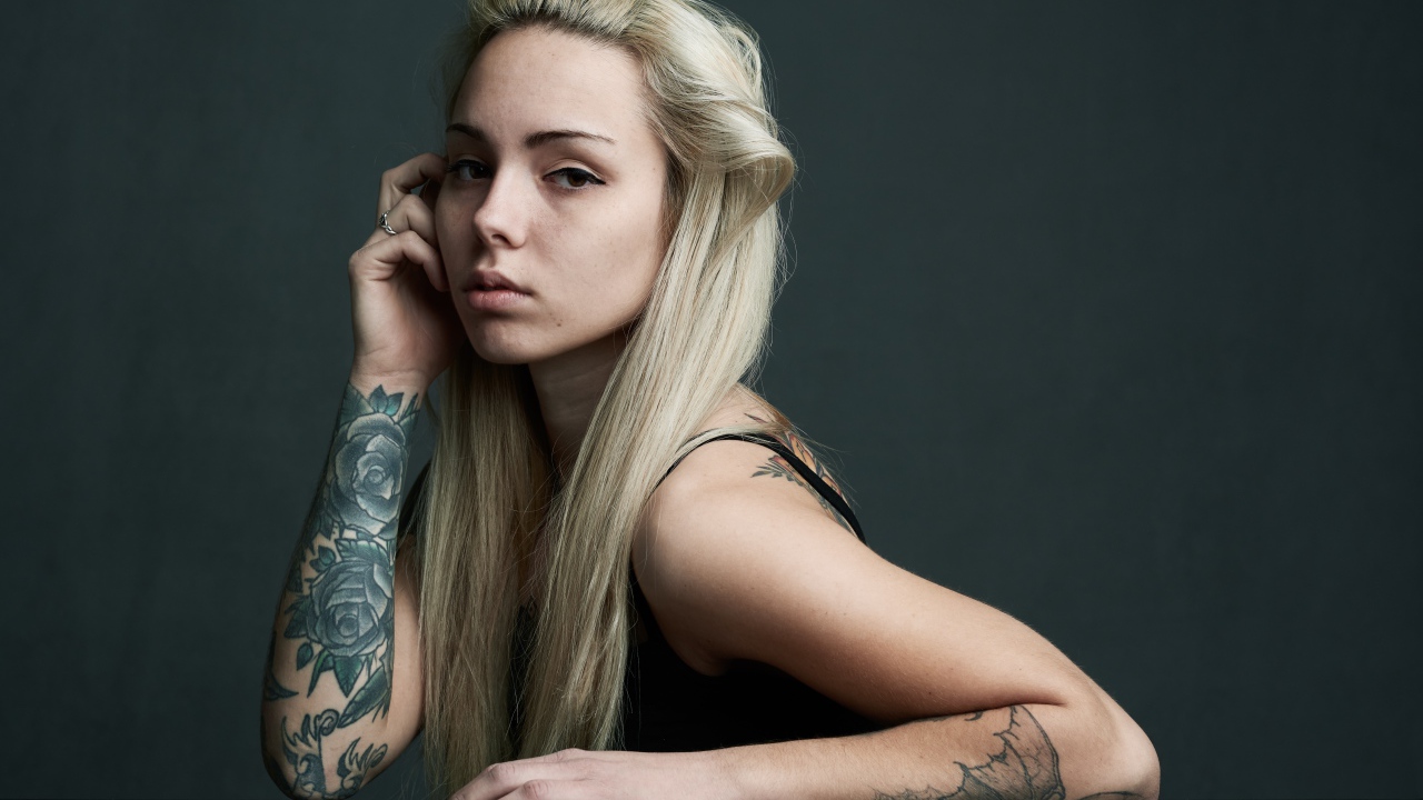 Молодая девушка с белыми волосами с татуировками на теле