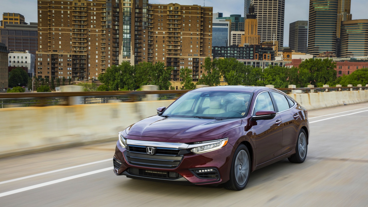 Бордовый автомобиль Honda Insight на фоне города