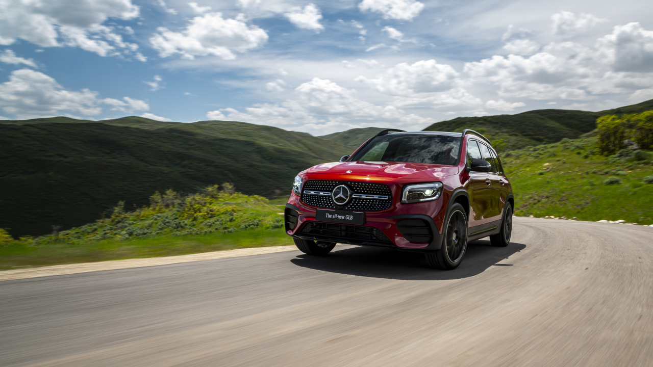 Красный автомобиль Mercedes-Benz GLB-Class  на фоне зеленых холмов