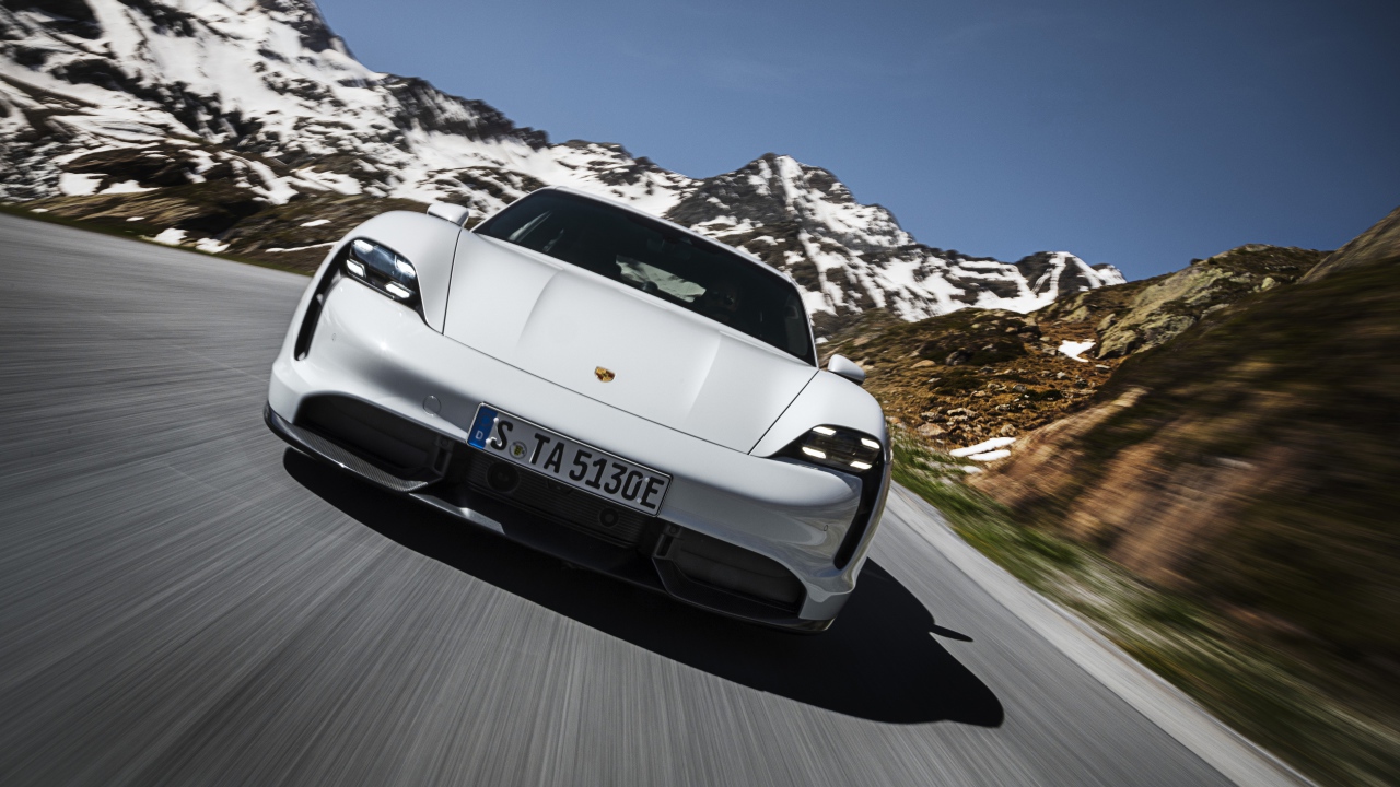 Белый автомобиль Porsche Taycan Turbo S 2019 года на фоне заснеженных гор