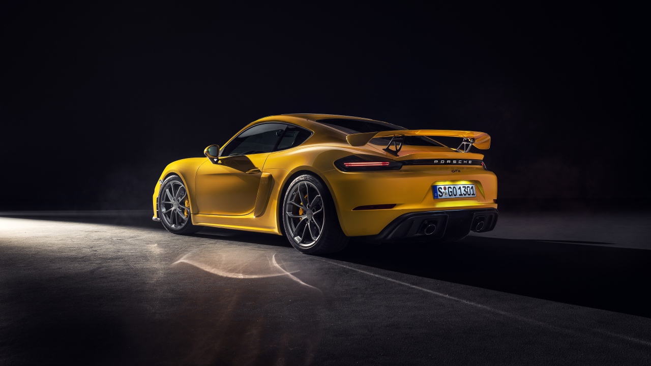 Желтый автомобиль Porsche 718 Cayman GT4, 2019 года вид сзади