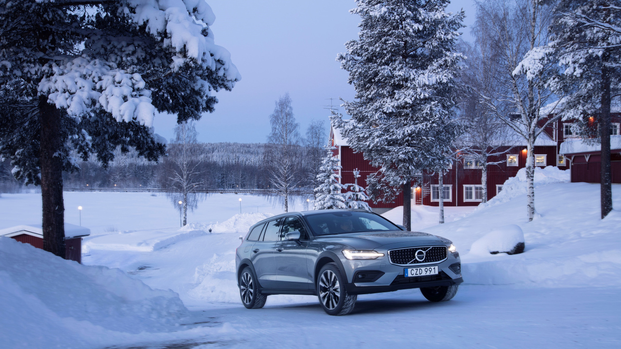 Автомобиль Volvo V60 на фоне заснеженных деревьев 